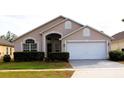 Tan house with white garage door and landscaping at 1068 Lake Berkley Dr, Kissimmee, FL 34746