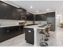 Modern kitchen with dark cabinets, an island, and stainless steel appliances at 1560 Flange Dr, Davenport, FL 33896