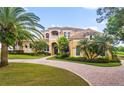 Impressive two-story home with palm trees and a brick driveway at 1515 Sunset Pointe Pl, Kissimmee, FL 34744