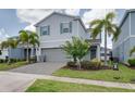 Charming home features two-car garage, paved driveway, and lush landscaping with palm trees at 1607 Kona Ln, Davenport, FL 33897