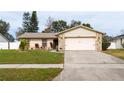 Tan one-story house with pink garage door and stone accents. Landscaped yard at 3618 Willow Lake Ct, Saint Cloud, FL 34769