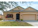 Tan house with a two-car garage and landscaping at 5589 Sycamore Canyon Dr, Kissimmee, FL 34758
