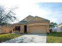 Tan house with a two-car garage and landscaping at 5589 Sycamore Canyon Dr, Kissimmee, FL 34758