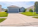 Well-maintained single-story home featuring a spacious driveway, lawn, and a gray exterior at 6144 Forest Ridge Way, Winter Haven, FL 33881