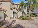 Two-story home with dark gray door and paver driveway, and palm trees at 220 Brunello Dr, Davenport, FL 33897