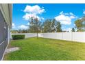 Grass backyard with white vinyl fence and two small trees at 3074 White Horse Ct, Kissimmee, FL 34746