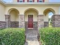 Elegant front porch with arched entryway, stone columns, and lush landscaping at 993 Suffolk Pl, Davenport, FL 33896