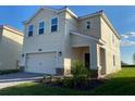 Two-story house with a beige exterior, two-car garage, and landscaping at 1144 Trappers Trail Loop, Davenport, FL 33896