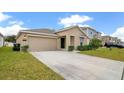 Tan house with black door, two-car garage, and manicured lawn at 1274 Fury St, Davenport, FL 33837