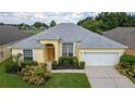 Single-Gathering home with gray roof, driveway, and landscaped yard at 135 Langham Dr, Davenport, FL 33897
