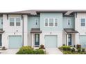 Two-story townhome with light teal siding, two-car garage, and landscaping at 1481 Discovery St, Davenport, FL 33896
