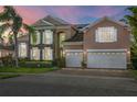 Two-story house with a three-car garage and solar panels at dusk at 2136 Laurel Blossom Cir, Ocoee, FL 34761
