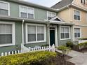 Two-story townhome with green siding, white picket fence, and landscaping at 2200 San Christabolo Dr # 106, Kissimmee, FL 34741