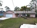 Pink house with a white garage door and palm trees at 1186 Laguna Cir, St Cloud, FL 34771