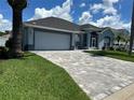 Single-story home with gray exterior, paved driveway, and lush landscaping at 148 Joewood Trl, Davenport, FL 33837