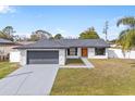 Newly renovated home with gray garage door and orange front door at 202 Cobalt Dr, Kissimmee, FL 34758