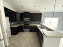 Modern kitchen featuring dark cabinetry, stainless steel appliances, and a breakfast bar at 228 Whispering Pines Way, Davenport, FL 33837