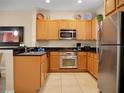 Bright kitchen featuring stainless steel appliances, tan cabinets, and stylish decor at 2717 Coupe St, Kissimmee, FL 34746