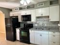 Updated kitchen with white cabinets, granite counters, and black appliances at 710 Michigan Ct # 2, St Cloud, FL 34769