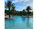 Large community pool with palm trees, lounge chairs and blue skies in a tropical paradise setting at 2937 Bella Flore Ter, New Smyrna Beach, FL 32168