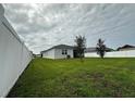 A spacious backyard showcasing a large lawn, a white privacy fence, and scattered trees, perfect for outdoor activities at 446 Citrus Isle Loop, Davenport, FL 33837