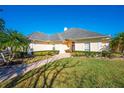 Tan house with a red door, palm trees, and a brick walkway at 5666 Merlin Way, St Cloud, FL 34772