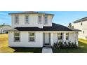 Two-story house with gray roof and white exterior, featuring a walkway and landscaping at 2668 Trafalgar Blvd, Kissimmee, FL 34758