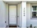 White front door with gray trim and black house numbers at 2668 Trafalgar Blvd, Kissimmee, FL 34758