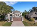Two-story house with brown garage door and tree-lined street at 336 Del Sol Ave, Davenport, FL 33837