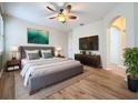 Spacious bedroom with a king-size bed, hardwood floors, and large TV at 6826 Goldflower Ave, Harmony, FL 34773