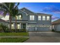 Two-story house with gray siding, three-car garage, and landscaped yard at dusk at 8870 Backspin Ln, Champions Gate, FL 33896