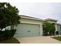 Two-car garage with light green doors and landscaping at 1028 Merrimack Blvd, Davenport, FL 33837