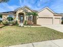 Tan house with brown roof, three-car garage, and landscaped yard at 125 Viola Dr, Auburndale, FL 33823