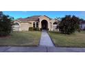 Tan house with a walkway leading to the front door, lush landscaping and a neatly kept lawn at 1534 Gants Cir, Kissimmee, FL 34744