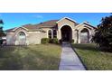 Tan house with a walkway leading to the front door, lush landscaping and a neatly kept lawn at 1534 Gants Cir, Kissimmee, FL 34744