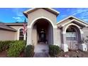 Front porch with arched entryway, dark door and American flag at 1534 Gants Cir, Kissimmee, FL 34744