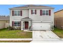 Inviting two-story home with red shutters, a manicured lawn, and a convenient two-car garage at 1634 Reddish Egret Ct, Davenport, FL 33897