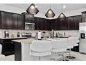 Modern kitchen with dark cabinets, granite counters, and island seating at 2190 Lelani Cir, Davenport, FL 33897