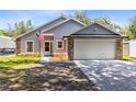 Gray house with stone accents, two-car garage, and American flag at 4755 Oakwood Dr, St Cloud, FL 34772