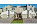 Tan three-story townhome with two-car garage, red door, and landscaping at 8879 Cabot Cliffs Dr # 103, Davenport, FL 33896