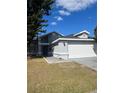 Gray house with white garage door and landscaping at 136 Pinewood Cir, Kissimmee, FL 34743