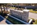 Stone sign at the community entrance featuring manicured landscaping and palm trees at 2276 Centerra Loop, Kissimmee, FL 34741
