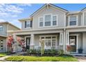 Inviting two-story townhome featuring a covered front porch and colorful tropical foliage at 2276 Centerra Loop, Kissimmee, FL 34741