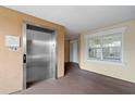 Well-lit hallway with elevator access and a view to a comfortable-looking common space at 7658 Whisper Way # 202, Reunion, FL 34747