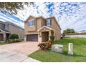 Tan two-story house with brown garage door and landscaping at 250 Pendant Ct, Kissimmee, FL 34747