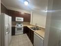 Well-lit kitchen featuring white appliances and dark wood cabinetry at 10583 Regent Square Dr # 1206, Orlando, FL 32825