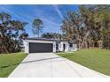 Modern house with gray garage door and driveway; grassy yard at 13142 Sw 43Rd Avenue Rd, Ocala, FL 34473