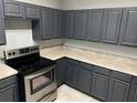 Updated kitchen with stylish dark gray cabinets, stainless steel appliances, and tile floors at 228 Remington Pl, Haines City, FL 33844