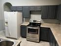 Kitchen featuring white refrigerator, stainless steel range, gray cabinets, and tile floors at 228 Remington Pl, Haines City, FL 33844