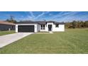 Modern home's exterior features a two-car garage and manicured lawn at 2571 Sw 153Rd Lane, Ocala, FL 34473